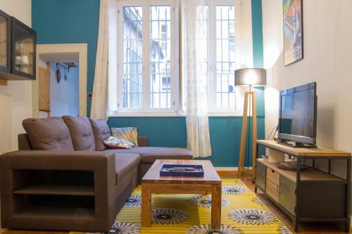 Una sala de estar con un sofá y un televisor. en L'air du temps - Centre historique Wifi TV, en Besançon