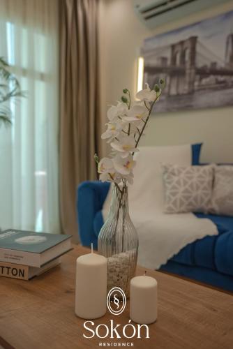 a vase with white flowers on a table with candles at Sokon Residence Madinaty in Madinaty