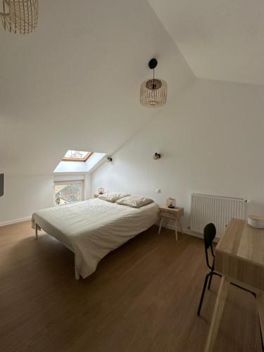 a white bedroom with a bed and a table at Appartement rénové hypercentre-Charleville-10p in Charleville-Mézières