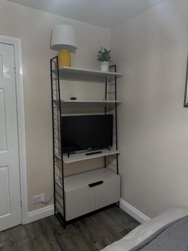 a television on a shelf in a room at Room at quiet location close to Belfast in Carnmoney