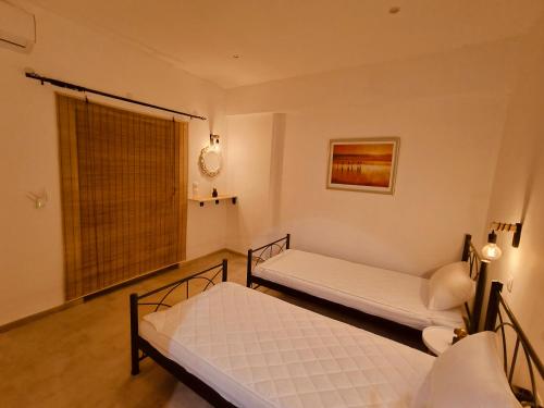 two beds in a room with a window at Relaxrooms, room with 2 single beds in Agios Georgios