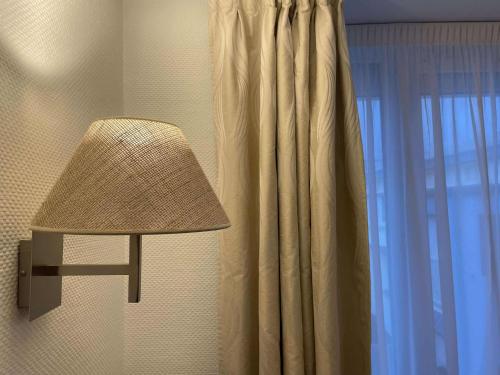 a lamp sitting next to a window with a curtain at Cit'Hotel Hôtel de France et d'Europe in Concarneau