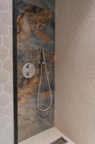 a shower in a bathroom with a stone wall at SULO VIP Spa in Atyraū