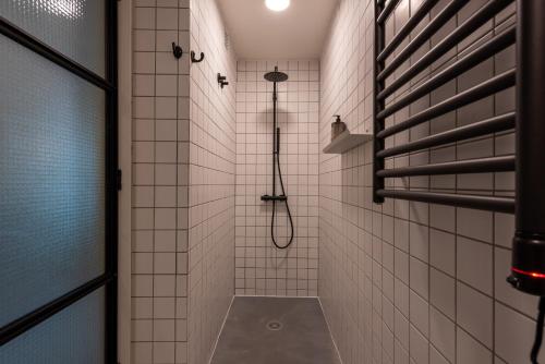 a walk in shower in a white tiled bathroom at The 98 Place Carcavelos in Carcavelos