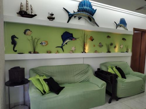 a living room with a green couch and shelves with fish at Apartamento, Praia Grande, Canto do Forte in Praia Grande