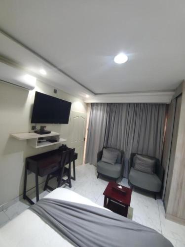 a room with a bed and a desk and a tv at Lovely 1 bedroom self catering apartment in Lusaka