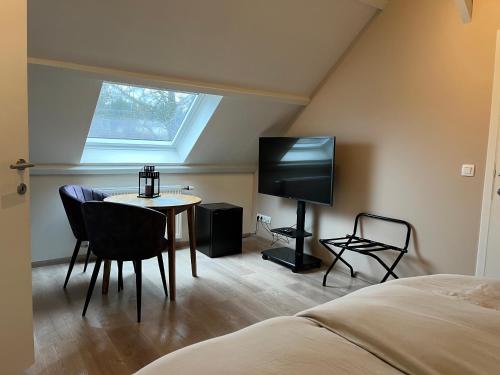 a bedroom with a bed and a table and a tv at Ecole Buissonnière in Vielsalm