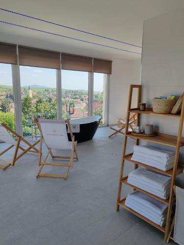 a room with a bath tub and a chair and towels at Villa Zéta Wine & Spa in Mád