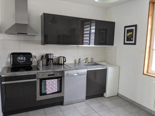 une cuisine avec un évier et une cuisinière four supérieur dans l'établissement Maison de vacances cosy, à Avranches