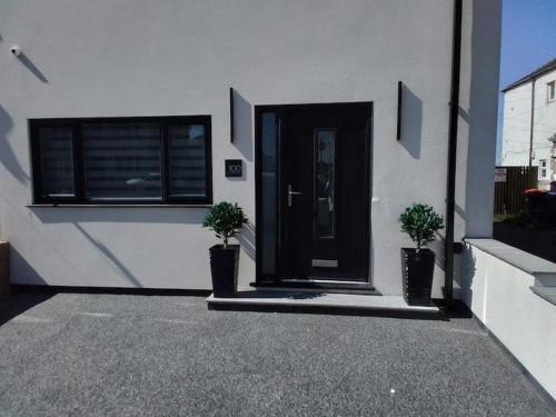 a house with a black door and two potted plants at Beachview apartment in Cleveleys