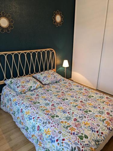 une chambre avec un lit avec un couvre-lit fleuri dans l'établissement Maison de vacances cosy, à Avranches
