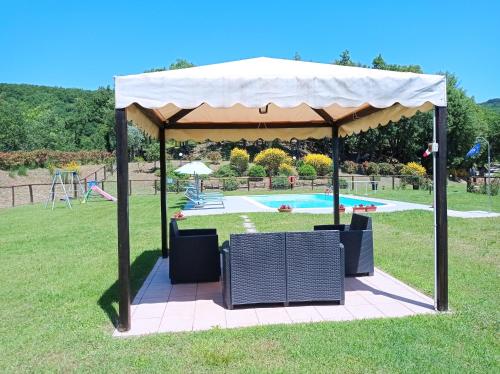 a gazebo with chairs under it in the grass at Agriturismo la Coccinella in Poggioni