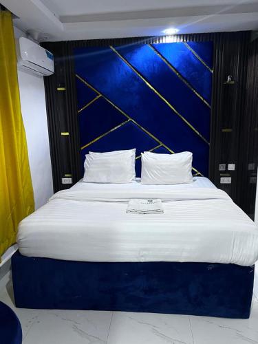 a large bed in a room with a blue wall at Villa Palazzo Hotel 2 in Ikeja