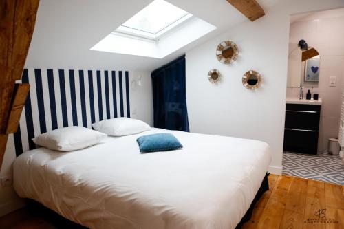 - une chambre avec un grand lit blanc et une lucarne dans l'établissement Le Jardin de Beau Pré - App 3-2 - Centre ville, à Perpignan