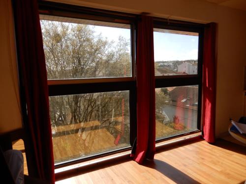Cette chambre dispose de 2 grandes fenêtres avec des rideaux rouges. dans l'établissement Voilà un joli studio toulousain !, à Toulouse