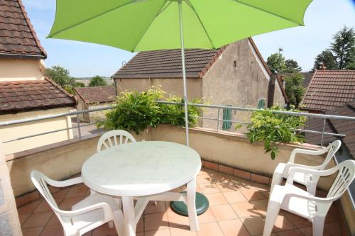 d'une table et de chaises sur un balcon avec un parasol vert. dans l'établissement Gite La Petite Maison - au coeur des vignes - Mercurey, à Saint-Martin-sous-Montaigu