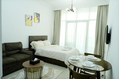 a bedroom with a bed and a couch and a table at Cozy Private Studio -Near Beach -City View -Downtown Sharjah - Pool & Gym in Sharjah