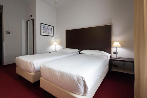 a hotel room with two beds and two lamps at Art Hotel Olympic in Turin