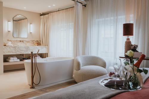 a bathroom with a bath tub and a chair and a chair at The Burgundy - Boutique B&B in Bruges