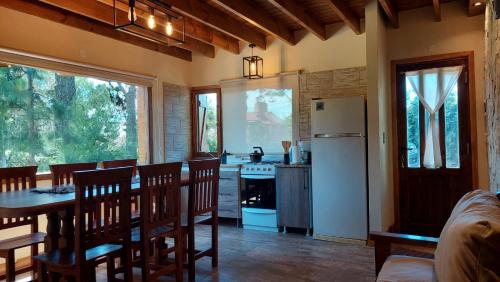 a kitchen and dining room with a table and a refrigerator at Cabañas Altos del Bosque in Mar del Plata