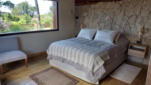 a bedroom with a bed and a stone wall at Cabañas Altos del Bosque in Mar del Plata