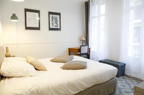 - une chambre avec un lit blanc et des oreillers dans l'établissement L'Olivier de Beau Pré - App 1-2 - Centre ville, à Perpignan
