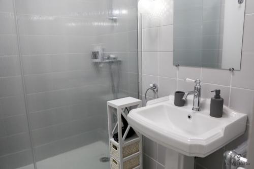 une salle de bain blanche avec un lavabo et un miroir dans l'établissement L'Olivier de Beau Pré - App 1-2 - Centre ville, à Perpignan