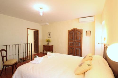 une chambre avec un grand lit blanc et une chaise dans l'établissement Casa Giulia - Duplex Eva, à LʼÎle-Rousse