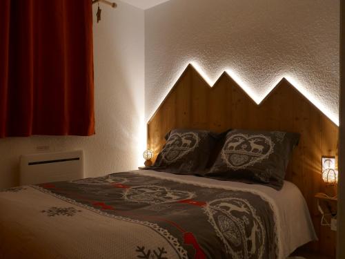 - un lit avec une tête de lit en bois et 2 oreillers dans l'établissement Aussois 4 personnes, à Aussois