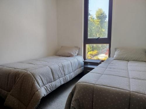 a bedroom with two beds and a window at Pinares Vista Lago in Pucón