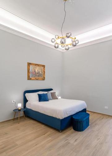 a bedroom with a blue bed and a chandelier at Palazzo Galeoni Luxury Suites in Salerno