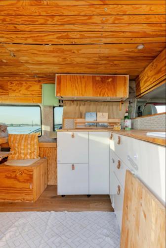 a kitchen with white cabinets and a wooden ceiling at Transi the Van in Düsseldorf