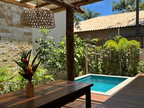 a patio with a wooden table and a swimming pool at Bahia Soul - Vilas de Maré - Taipu de Fora - Península de Maraú in Marau