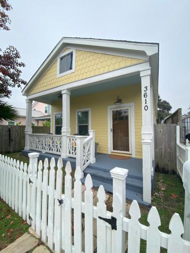 a small yellow house with a white picket fence at Vacation house in Galveston