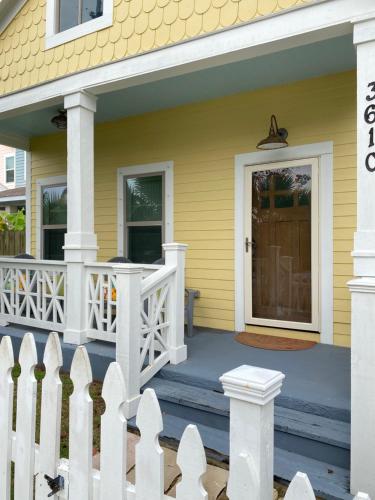 a yellow house with a white fence and a porch at Vacation house in Galveston