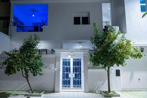 a white house with two trees in front of a door at CASABLU Apparte - Terrasse avec vue Sunset in Nabeul