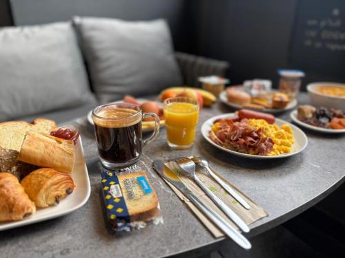a table topped with plates of breakfast foods and drinks at Cit'Hotel Le Cheval Blanc, Cognac Centre in Cognac