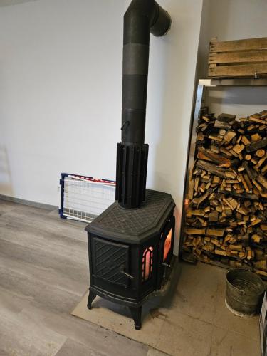 a black stove sitting next to a pile of wood at Baracek, Baraque in Horčápsko