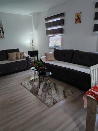 a living room with a black couch and a table at Sveti Luka- OBRADOVIĆ SOKAK 41 in Šimanovci