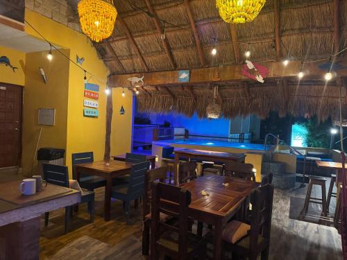 a restaurant with wooden tables and chairs and a pool at Casa Velero Puerto Morelos in Puerto Morelos