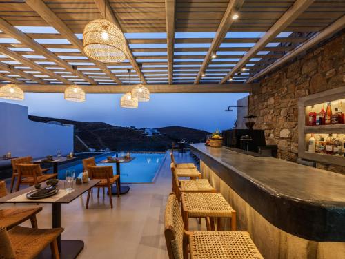 a restaurant with a bar with tables and chairs at Mykonos Residence Villas & Suites Merchia beach in Merchia Beach