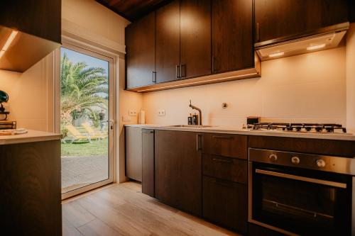 a kitchen with wooden cabinets and a large window at Country Club - Sto Estevao in Benavente