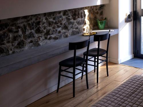 a table with two chairs in a room with a stone wall at Talè Restaurant & Suite in Piedimonte Etneo