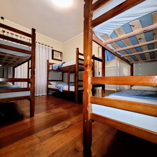 three bunk beds in a room with wooden floors at Blu Hostel in Blumenau