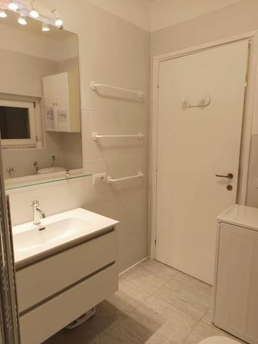a white bathroom with a sink and a mirror at Camilla House in Varenna