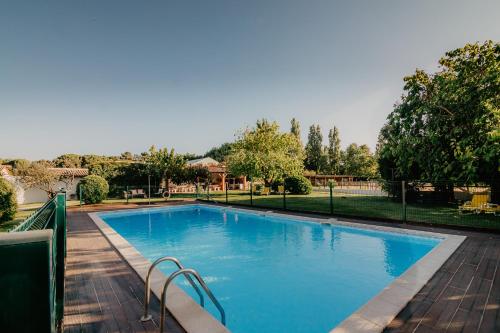 a swimming pool with blue water in a park at Country Club - Sto Estevao in Benavente