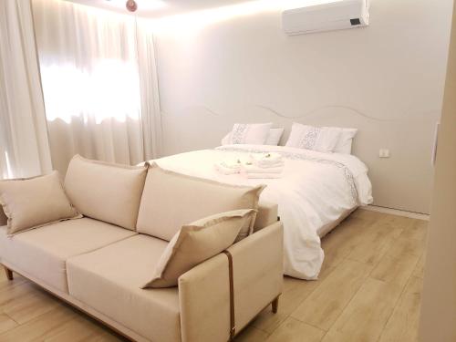 a white bedroom with a bed and a couch at Apart-hotel Theotókos Flats in Piumhi