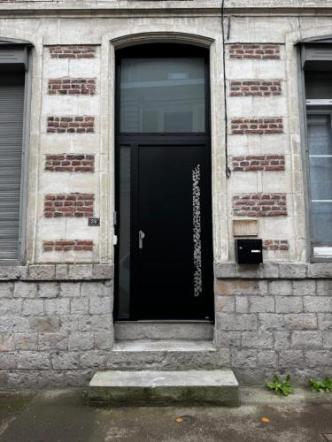 une porte noire sur un bâtiment en briques avec une fenêtre dans l'établissement La Suite green Douai, à Douai