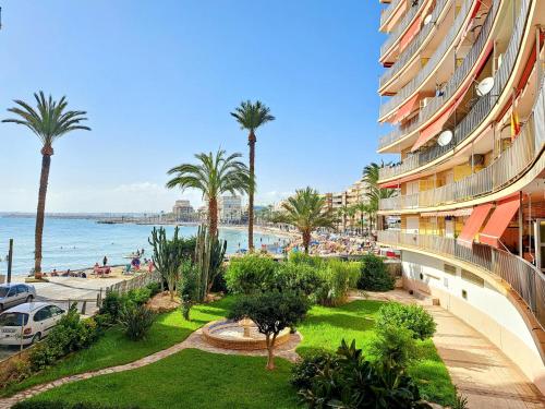 - une vue sur une plage bordée de palmiers et un bâtiment dans l'établissement Garden Beach Apartment, à Torrevieja