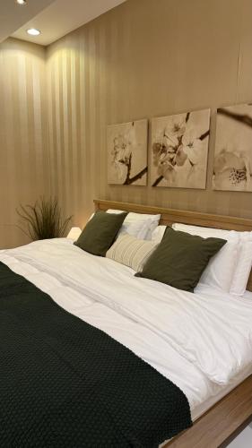 1 cama grande con sábanas blancas y almohadas verdes en شقة التّرف, en Taif